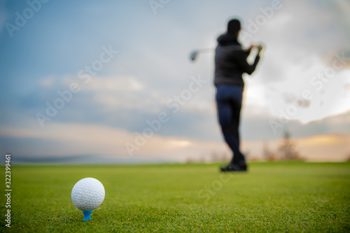 golfer on a green pitch batting golf ball