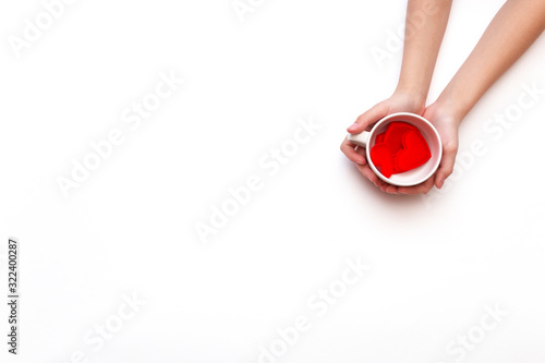 Top view of a white coffee Cup with a hearts in hands on a white background with copy space. Greeting card for Valentine's Day