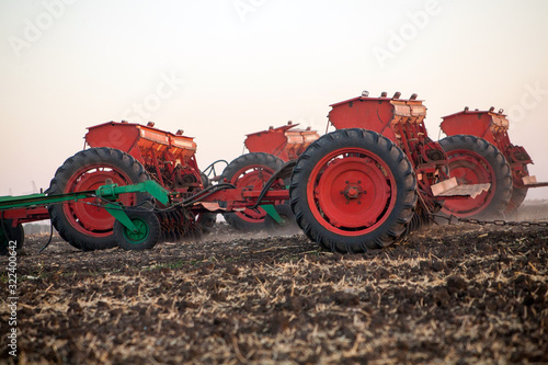 Agricultural mechanical seeders of grain crops. Tactor with a seeder sows grain in the field. A farmer on a tractor with a seeder processes the field. photo