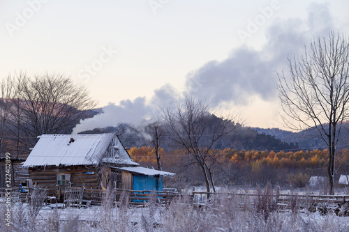 The village of Latin American Old Believers who returned to Russia in the Primorsky Territory. Wooden houses of Old Believers during a snowfall on a background of beautiful fields and mountains.
