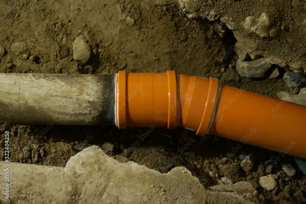 Replacing old cast iron sewer pipe with new pvc pipe. Stock Photo