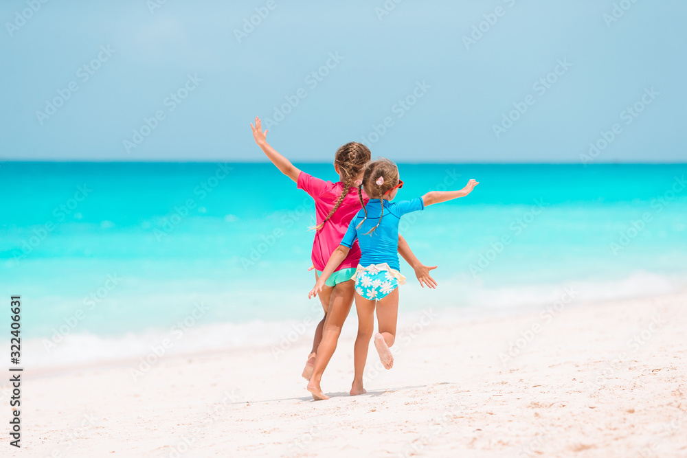 Little girls having fun at tropical beach playing together at shallow water Little girls having fun at tropical beach playing together at shallow water