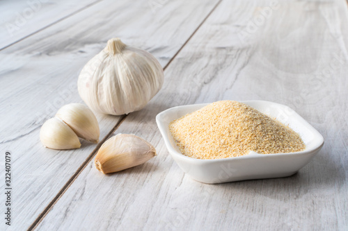 Dry granulated and fresh garlic on wooden table