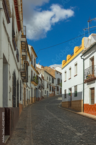 A small narrow street with white houses and blu sky in the old European city. Ronda, Andalusia, Spain.