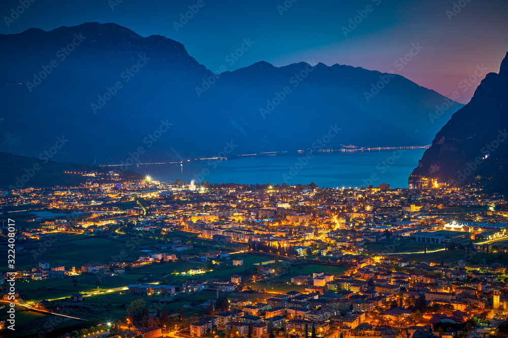 Arial Panorama of the gorgeous Garda lake surrounded by mountains in the in the autumn by night, View of the beautiful Riva del Garda town and Garda lake