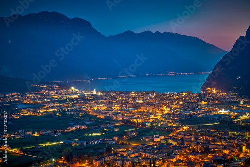 Arial Panorama of the gorgeous Garda lake surrounded by mountains in the in the autumn by night, View of the beautiful Riva del Garda town and Garda lake