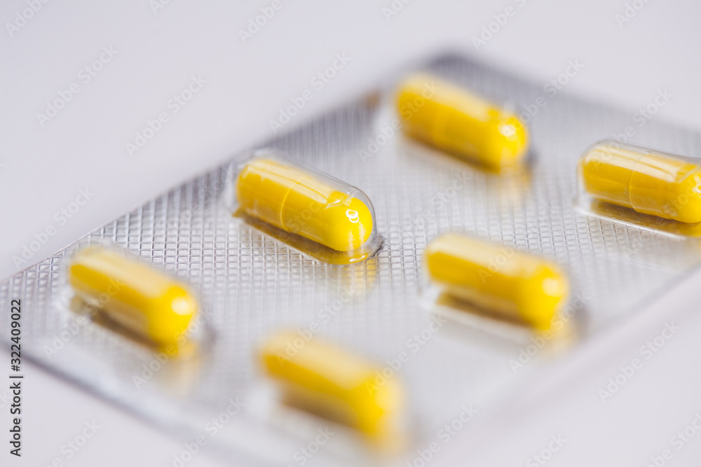 Close up of yellow tablets, pills in blister pack, medications drugs, macro, selective focus