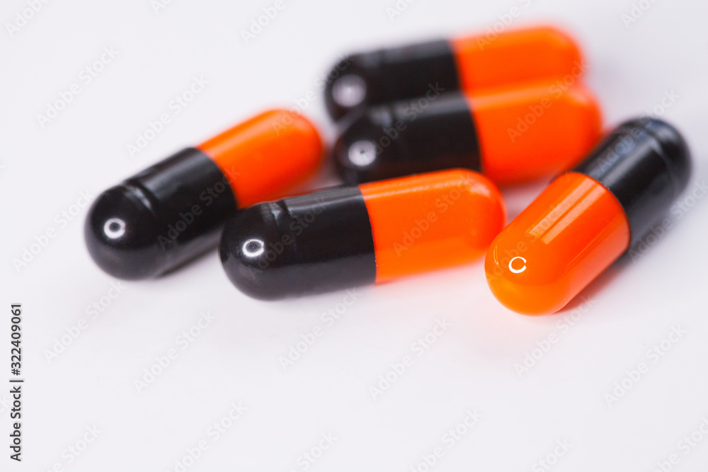 Close up of black and orange tablets, pills, medications drugs, macro, selective focus Close up of black and orange tablets, pills, medications drugs, macro, selective focus
