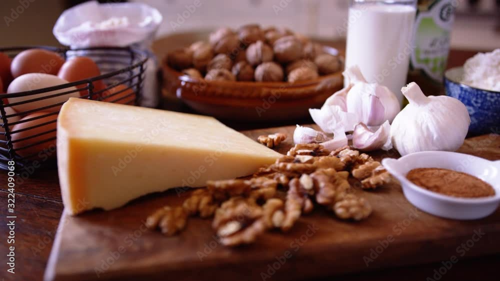 Fresh ingredients laid out in preparation for making homemade walnut ravioli pasta. Camera moves in slowly on the ingredients. Walnuts, parmesan cheese, cream, nutmeg, garlic. Fresh ingredients laid out in preparation for making homemade walnut ravioli pasta. Camera moves in slowly on the ingredients. Walnuts, parmesan cheese, cream, nutmeg, garlic.