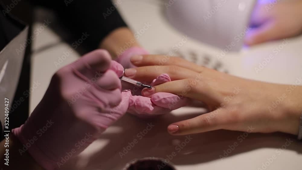 Closeup of women paints nails. Manicure nail art. Female works in pink gloves. Close up of woman's hands Closeup of women paints nails. Manicure nail art. Female works in pink gloves. Close up of woman's hands