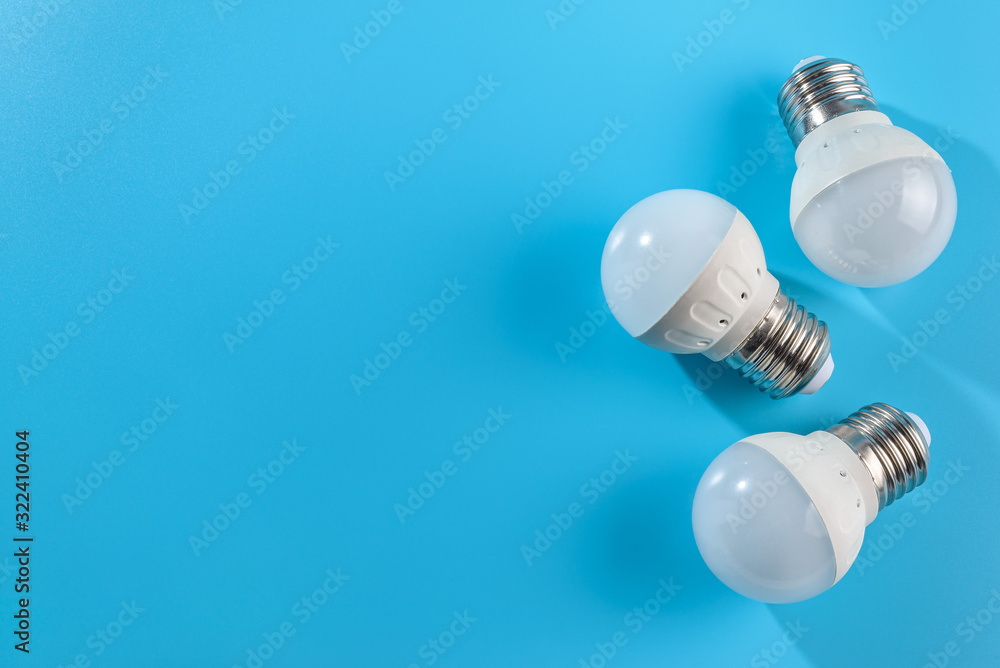 Three small white led energy saving led light bulbs on a blue background. Three small white led energy saving led light bulbs on a blue background.