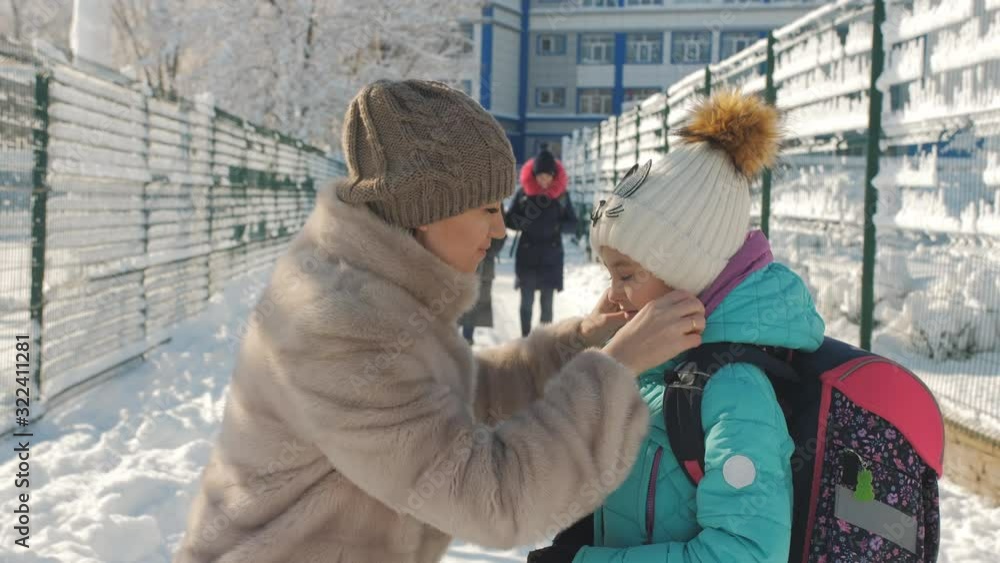 Mom adjusts hat a little daughter before sending her to school winter snow day. Mom adjusts hat a little daughter before sending her to school winter snow day.