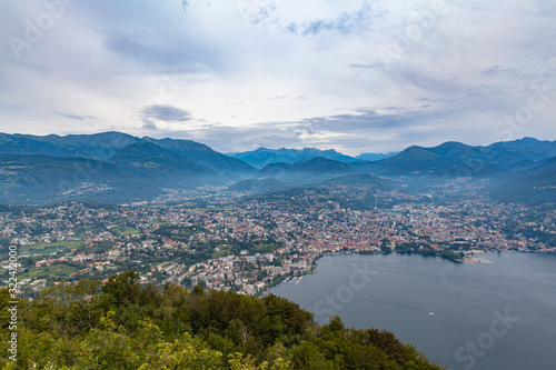 Stunning aerial panorama view of Lugano Lake, cityscape of Lugano, and Swiss Alps mountain on a cloudy summer day from top of Monte San Salvatore, Canton of Ticino, Switzerland