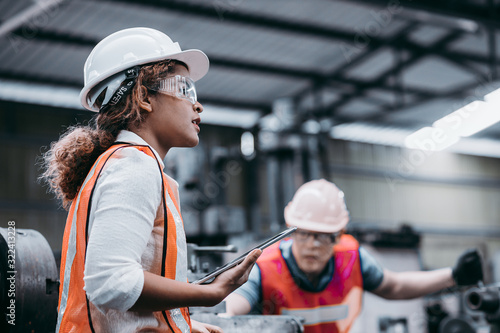 Obraz na płótnie Female industrial engineer wearing a white helmet while standing in a heavy indu