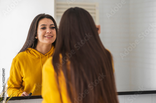 Mirror image of teenage girl applying mascara