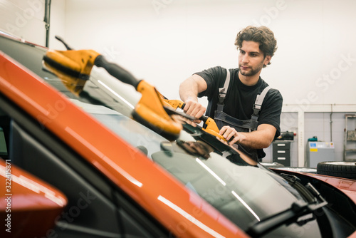 Car mechanic in a workshop changing car window photo