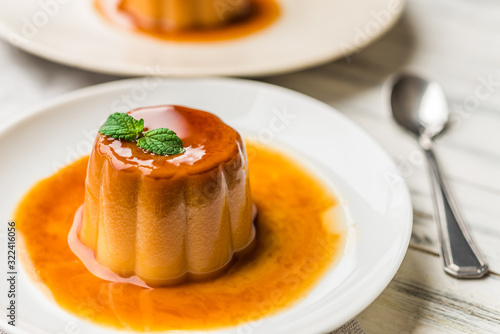 Canvas Print Close up of a flan creme caramel pudding with mint, a custard dessert against wh