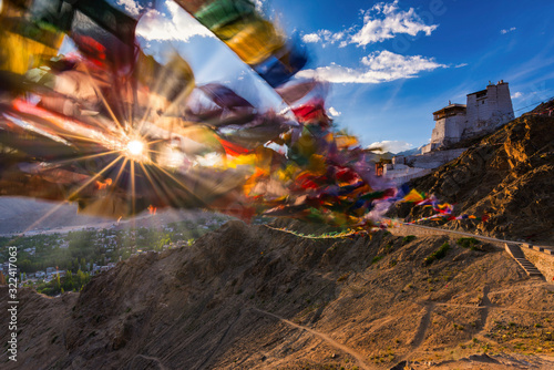 India, Jammu and Kashmir, Leh, Setting sun shining through prayer flags of Namgyal Tsemo Monastery photo