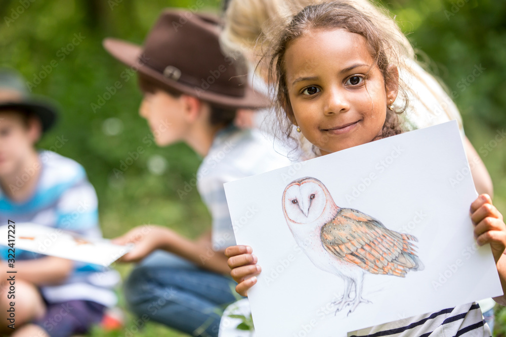 School children learning about animal species, girl holding picture of a bird School children learning about animal species, girl holding picture of a bird