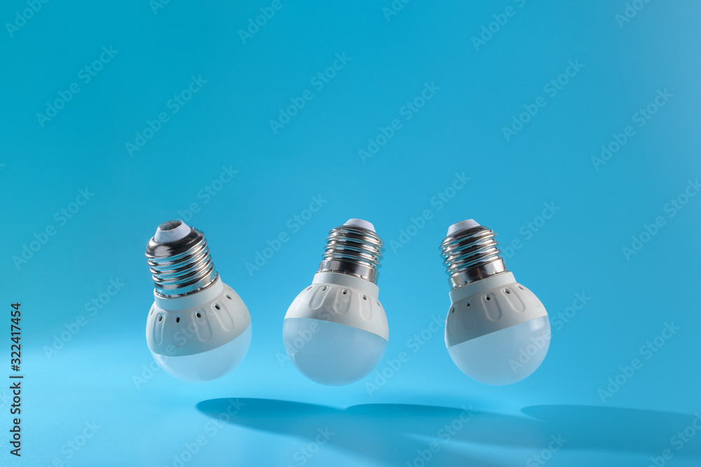 Three small white led energy saving led light bulbs on a blue background. Three small white led energy saving led light bulbs on a blue background.