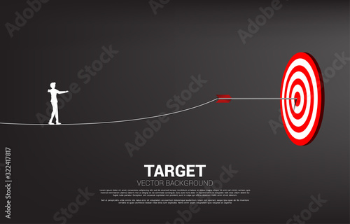 silhouette of businesswoman walk rope to arrow archery hit on the center of target. Concept of targeting and Business challenge.