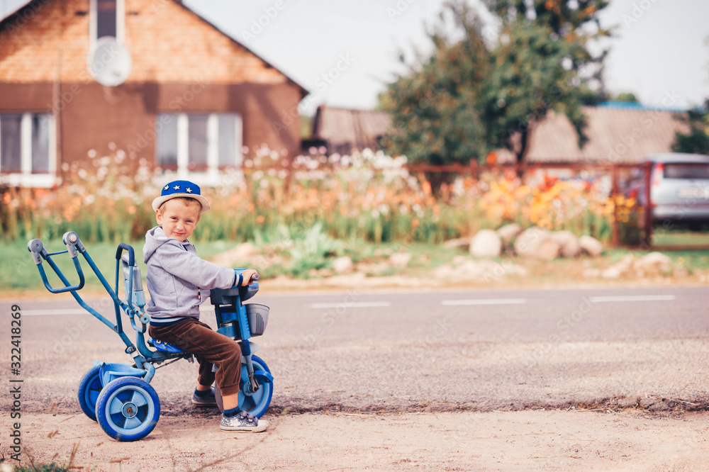 Handsome boy rides a bike on a village road and smiles Handsome boy rides a bike on a village road and smiles