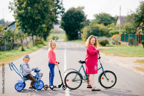 Brothers and sisters stands on the village road together with bicycles