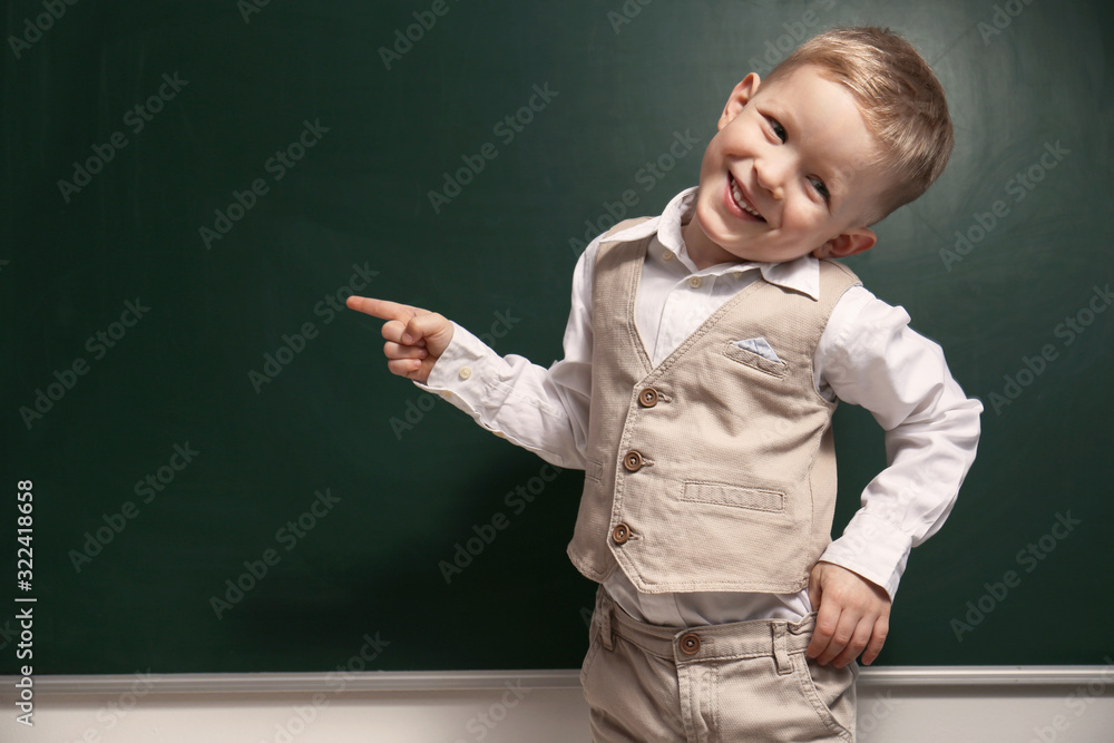 Funny little child near chalkboard, space for text. First time at school Funny little child near chalkboard, space for text. First time at school