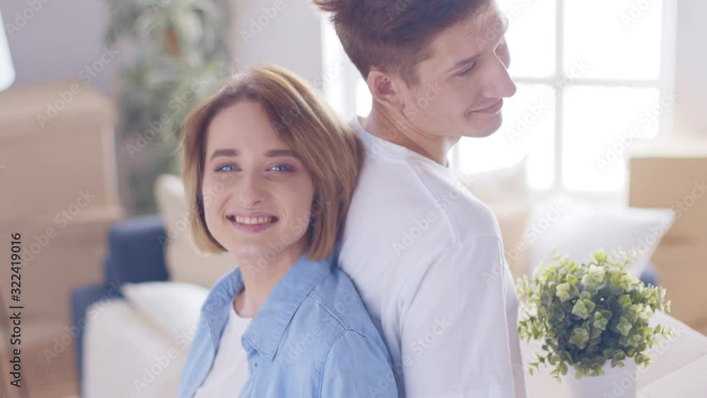 Young man and woman with carton boxes are entering room in new house.