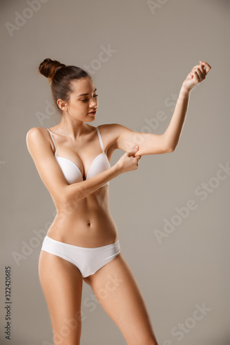 Woman pinching her skin on hand checking subcutaneous body fat layer © serhiipanin