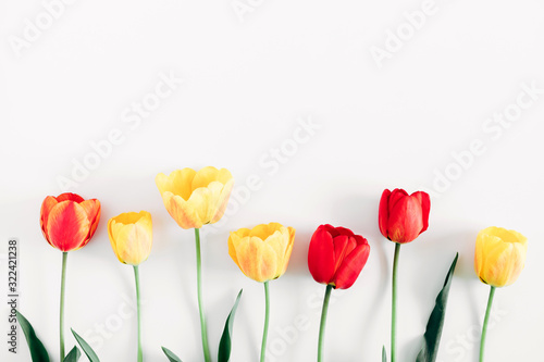 Beautiful composition of spring flowers. Yellow and red tulips flowers on white background. Valentine's Day, Easter, 8th march, Mother's Day. Flat lay, top view, copy space 