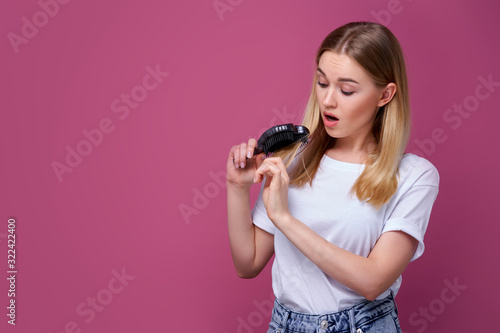 Beautiful woman is looking shocked at her hairbrush, blonde hair, young woman, adult