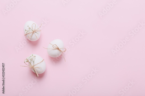 Three white Easter eggs with flowers on pink background