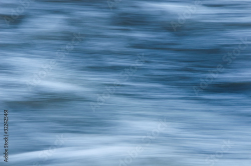 Texture of fast moving water, in blue, gray tones