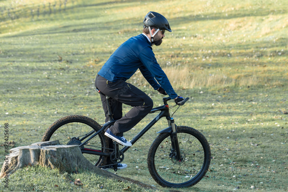 Obraz premium Cyclist in pants and fleece jacket on a modern carbon hardtail bike with an air suspension fork. The guy on the top of the hill rides a bike.