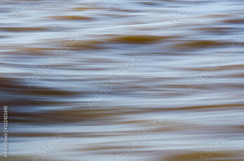 Texture of fast moving water, in yellowish soft tones.