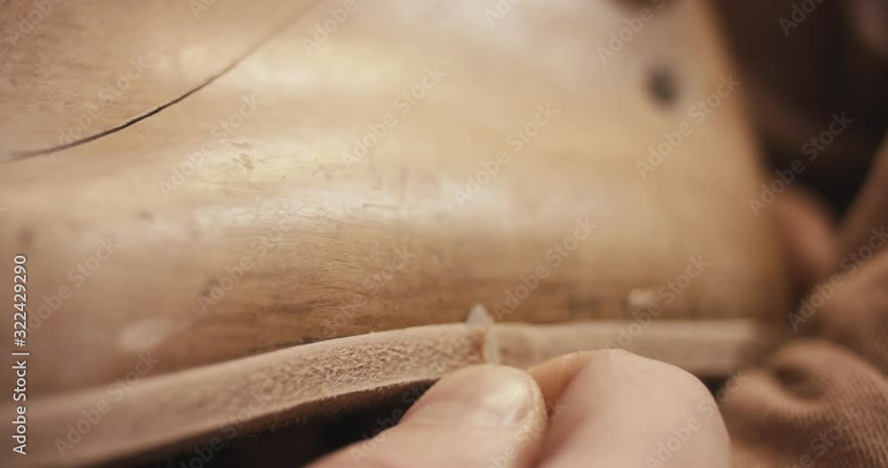 Traditional bespoke shoemaker cutting shaping leather insole on wooden shoe last with knife close up Traditional bespoke shoemaker cutting shaping leather insole on wooden shoe last with knife close up