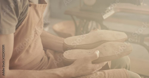 Traditional bespoke shoemaker cutting shaping checking leather insole on wooden shoe last with knife over the shoulder