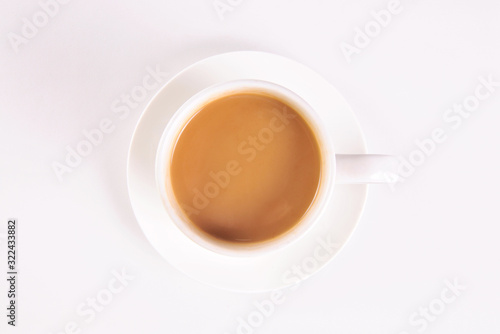 White cup of creamy coffee isolated on blue background. Top view.