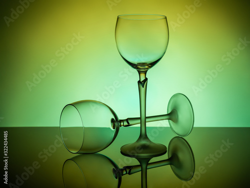 Two empty glasses on a green-lit table, one - lies