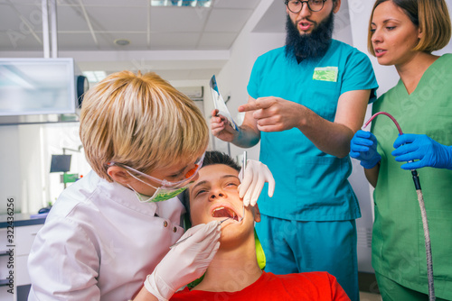 Professional team of dentists helping during  dental checkup of young boy patient