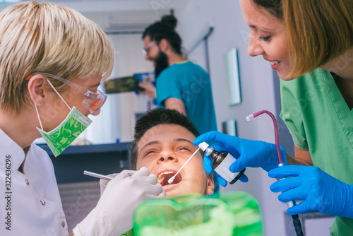Closeup picture of a female dentist examining teenage boy s teeth in the dental office.