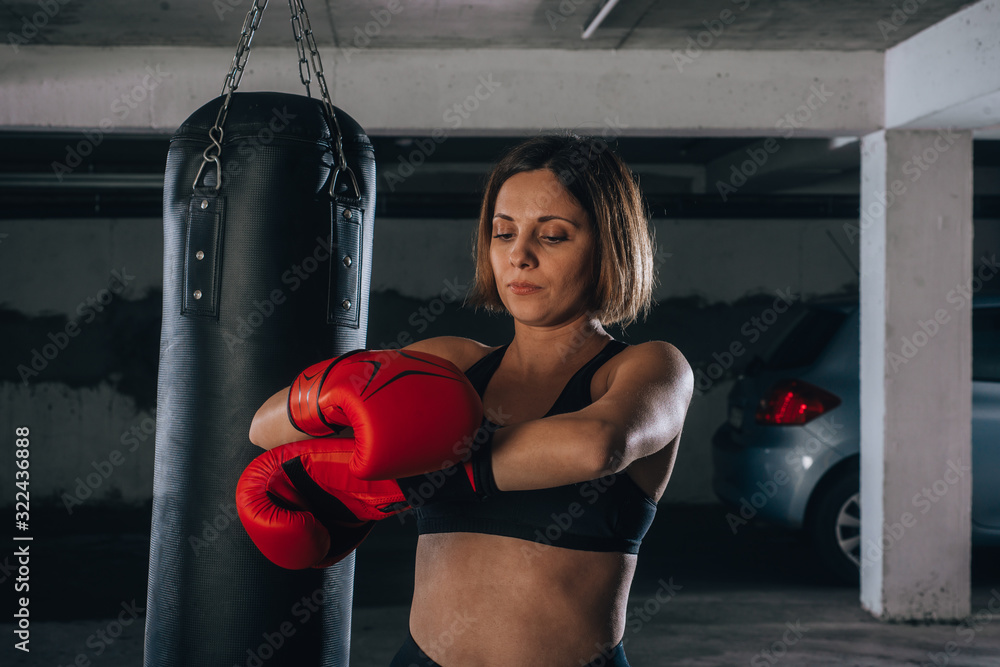 Confident young woman putting on her red boxing gloves