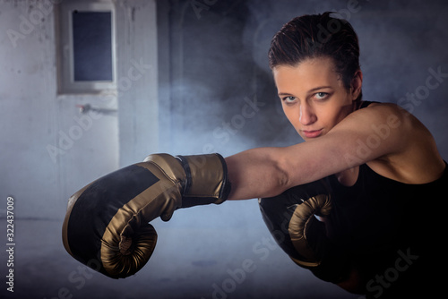 Closeup image of a female boxer punching with boxing gloves and looking at the camera