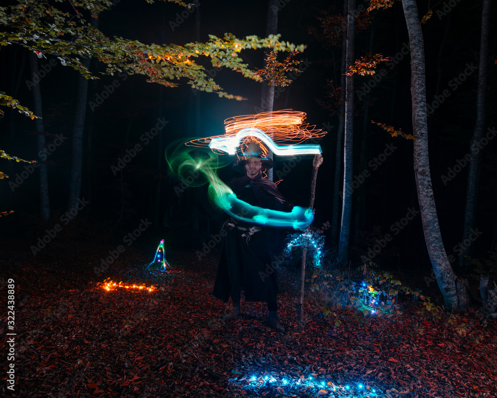 Sorcerer (magician) casting a spell while standing in the magical woods ...