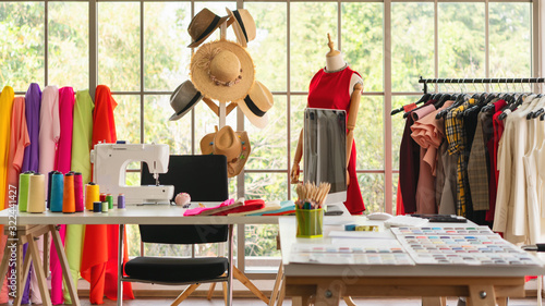 interior of dressmaker shop with dressmaking working desk and hanging rack with dress photo