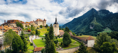 Scenic panoramic view of old medieval town of historic Gruyeres, home to the famous Le Gruyere cheese on a beautiful sunny day with clouds in summer, canton of Fribourg, Switzerland