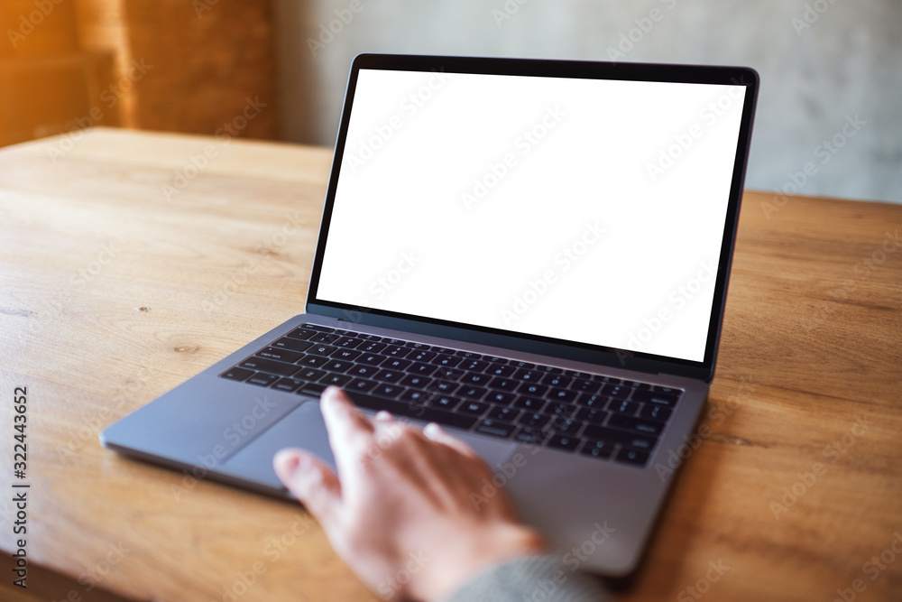 Mockup image of a woman using and touching on laptop computer touchpad with blank white desktop screen on wooden table Mockup image of a woman using and touching on laptop computer touchpad with blank white desktop screen on wooden table