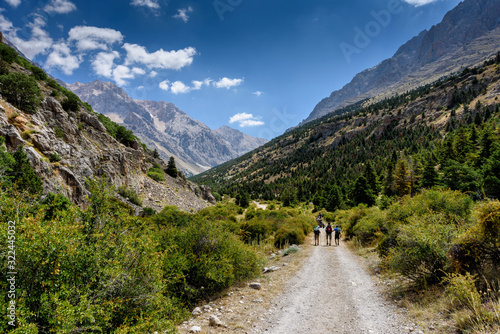 Turkey, Chamard - August 3, 2019: Tourists walk along the road through the mountain landscape in the Turkish national Park aladag in summer day, view from the back © kuzenkova