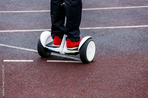 Teenager rides whirl on a hoverboard over park road